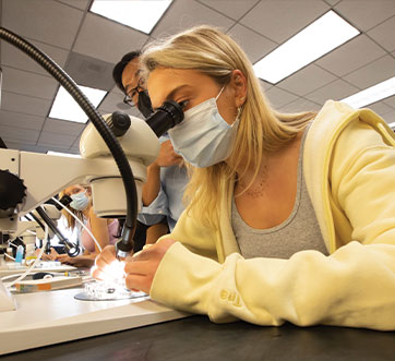 Photo of student on microscope. Links to Gifts That Pay You Income